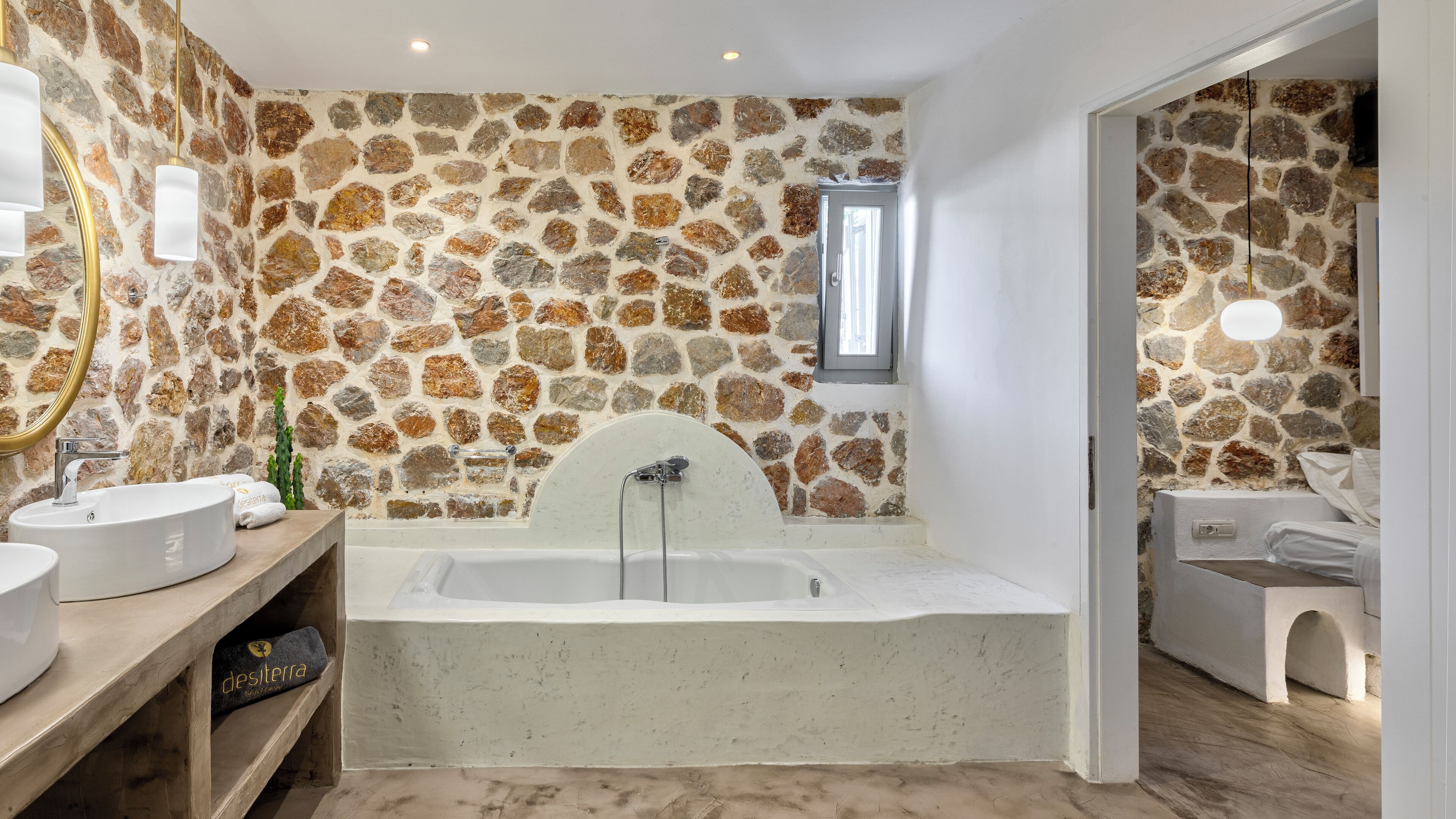 A bathroom with a stone wall, a bathtub, and a wooden vanity.