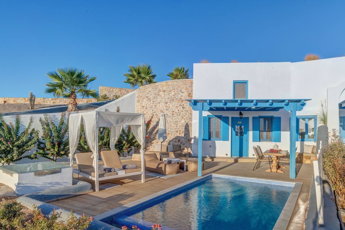 Ein Poolbereich mit einem weißen Gebäude, blauen Akzenten und einer Pergola.