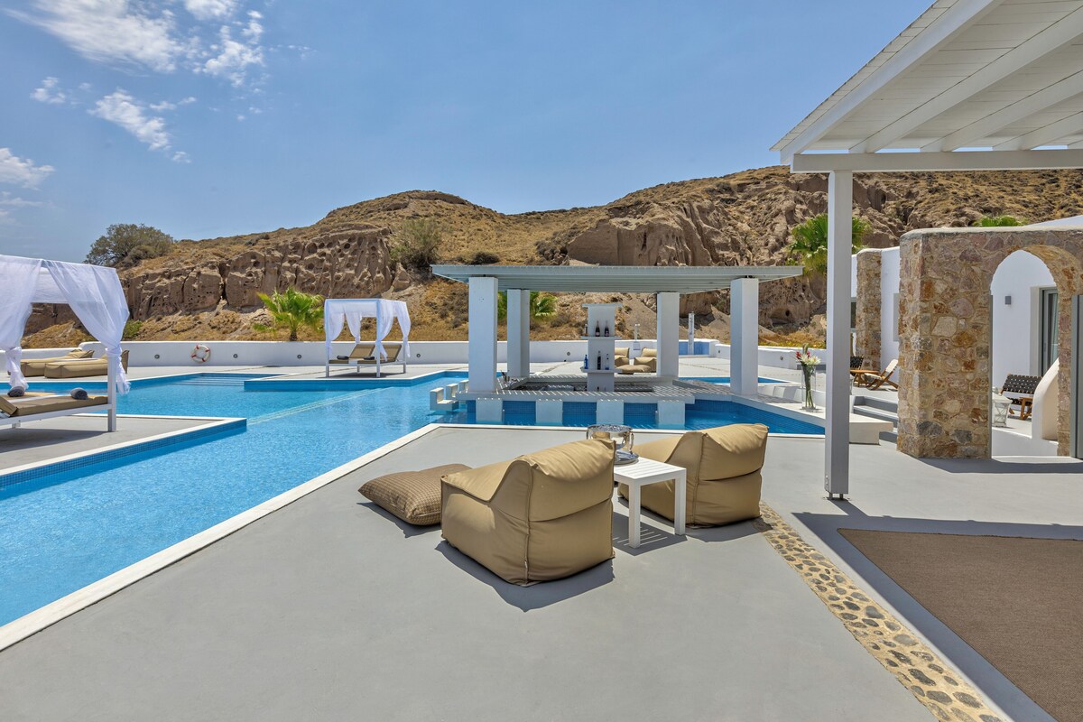 Un área junto a la piscina con sillones reclinables, una mesita y una pérgola.