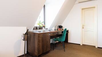 A small, modern kitchen with a wooden countertop, a teal chair, and a window with blinds.