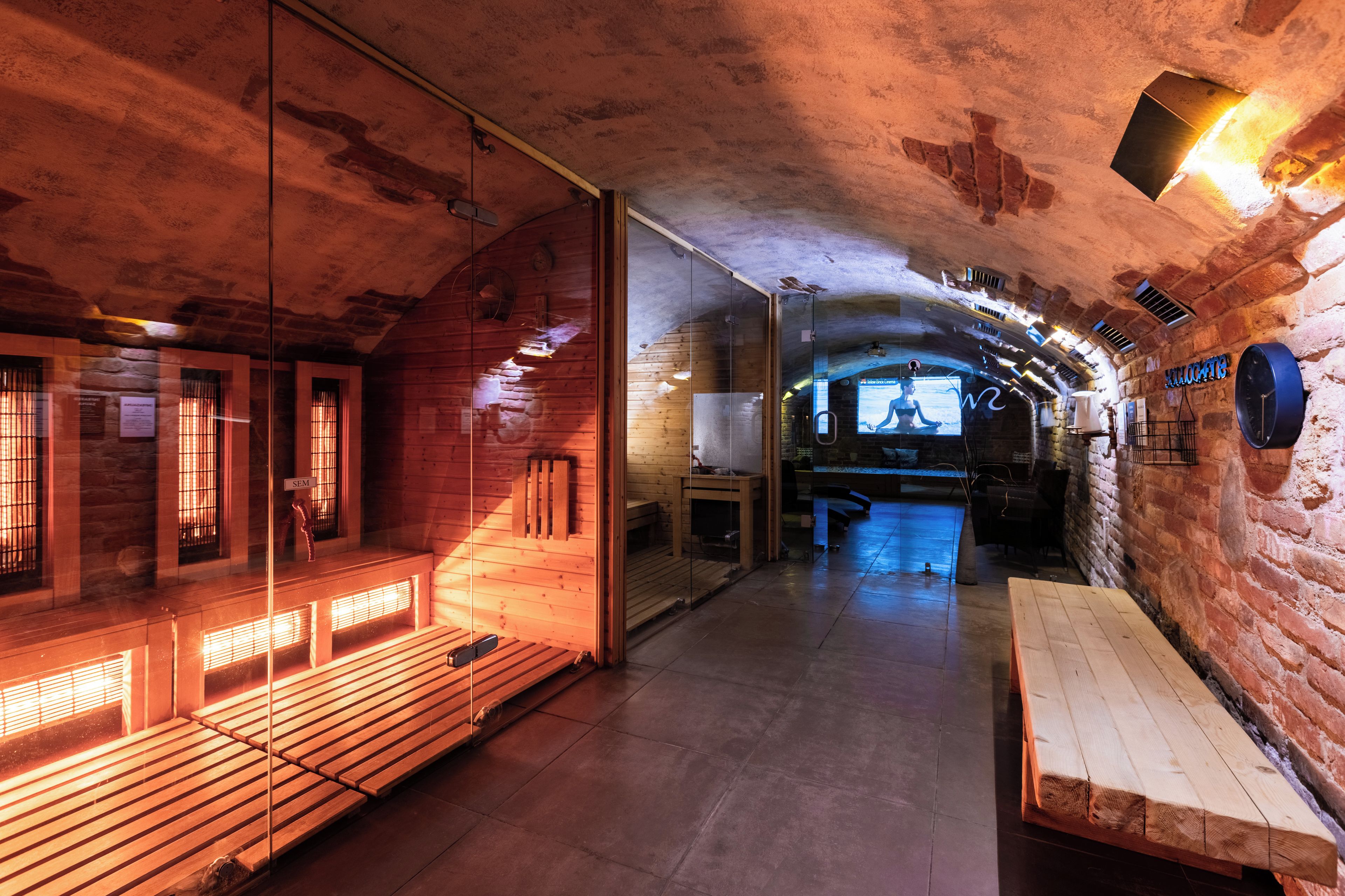 Un interior rústico y tenuemente iluminado, con bancos de madera y una pared de piedra.