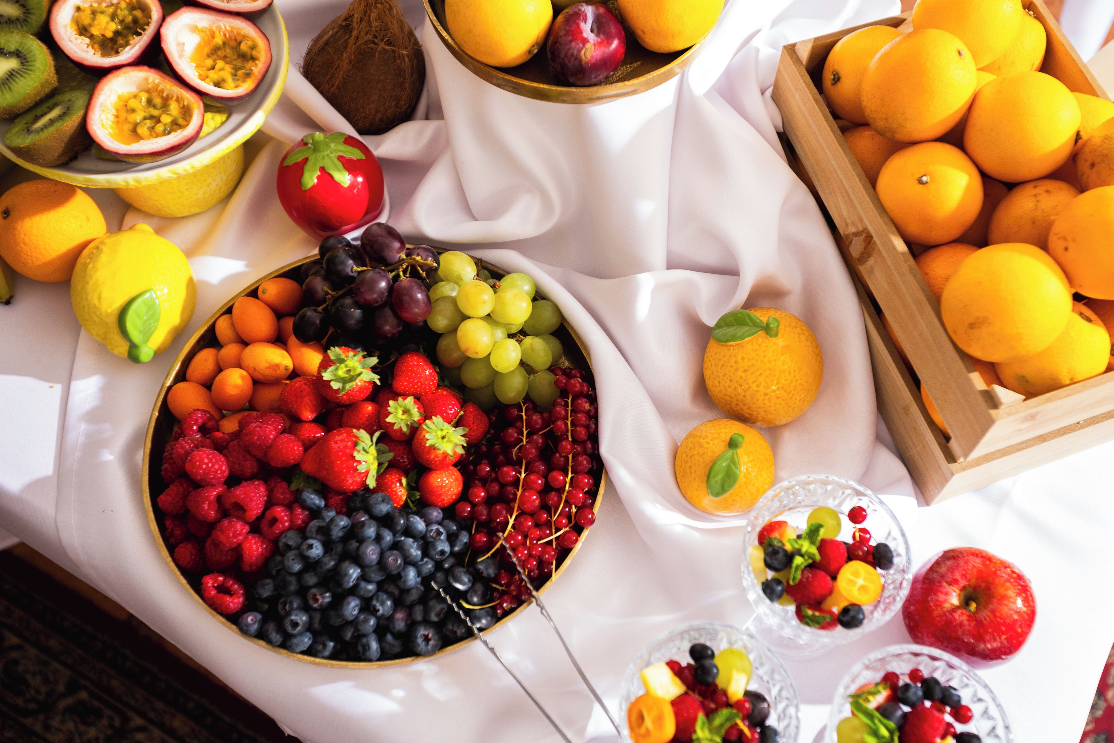 Una mesa con frutas variadas y un bol de bayas mixtas.