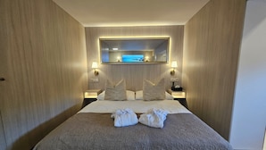 A hotel room with a large bed, two nightstands, a wall-mounted TV, and a mirror above the bed. - Penzión & Wellness Zoborská (Nitra)