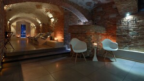 An interior with a brick archway leading to a seating area with two white chairs and a small table. - Penzión & Wellness Zoborská (Nitra)