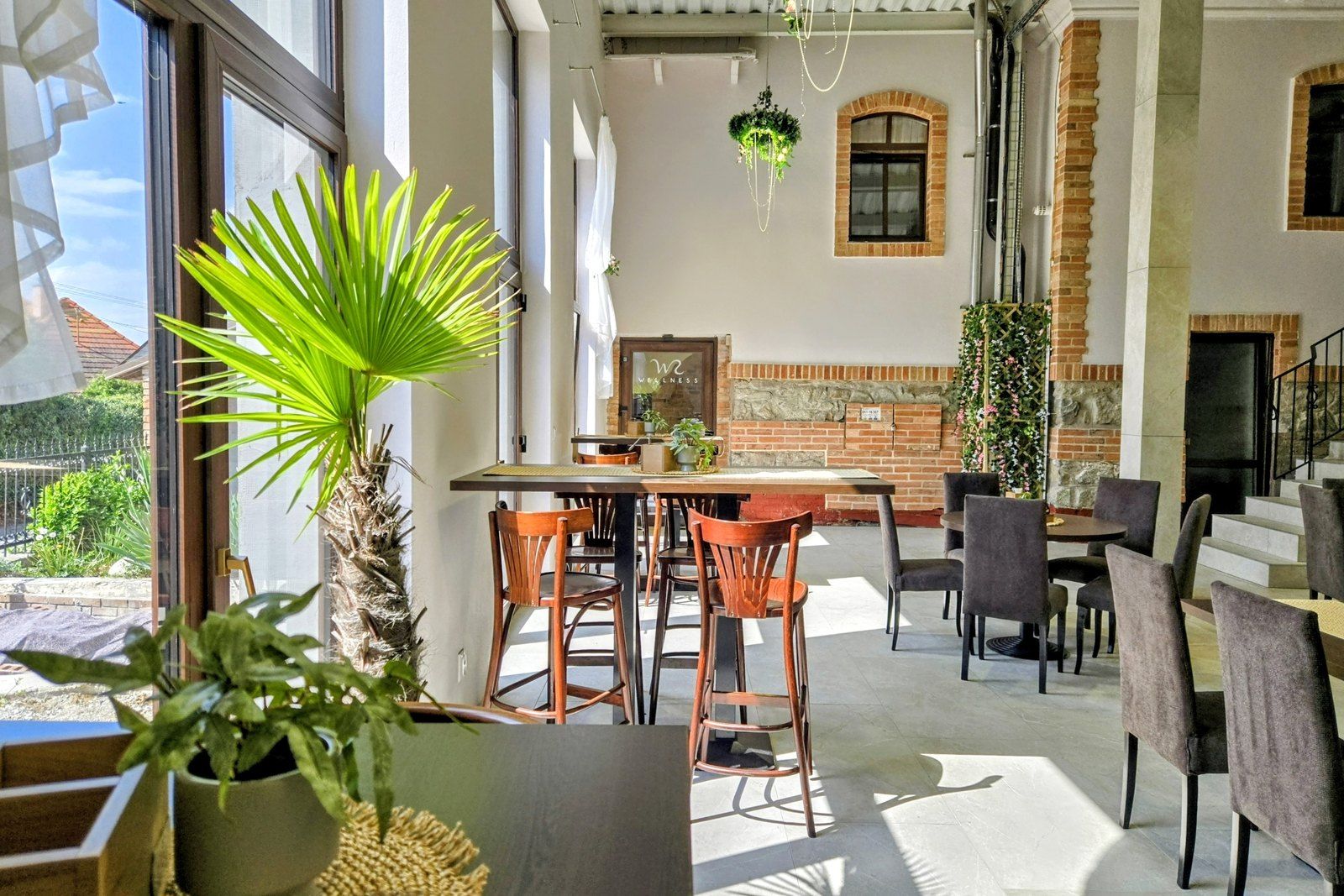 A spacious dining area with a brick wall, wooden chairs, and a large window.