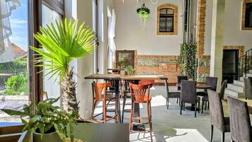A spacious dining area with a brick wall, wooden chairs, and a large window.