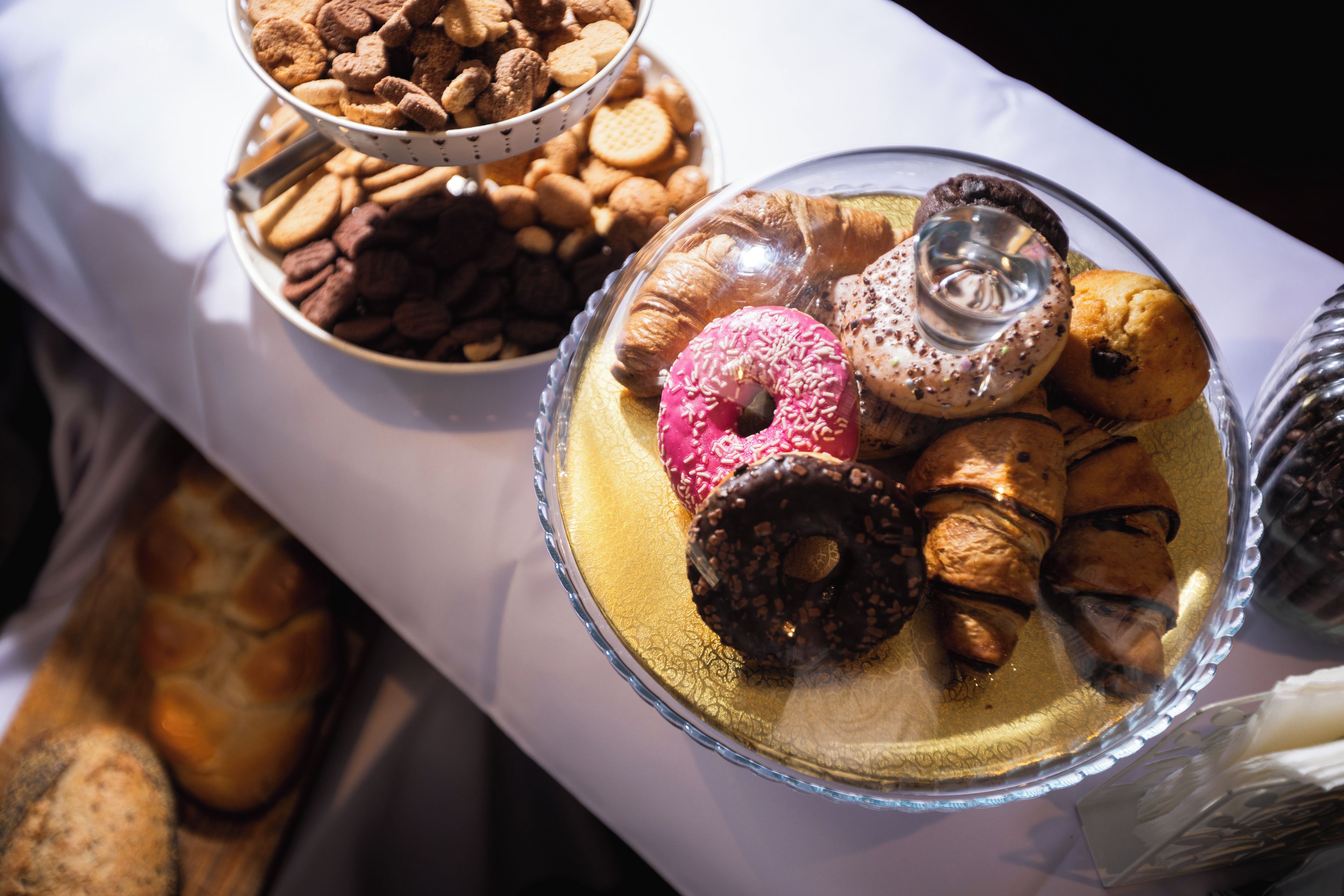 Une variété de produits de boulangerie, notamment des beignets, des biscuits et des pâtisseries, présentés dans de jolis bols en verre.