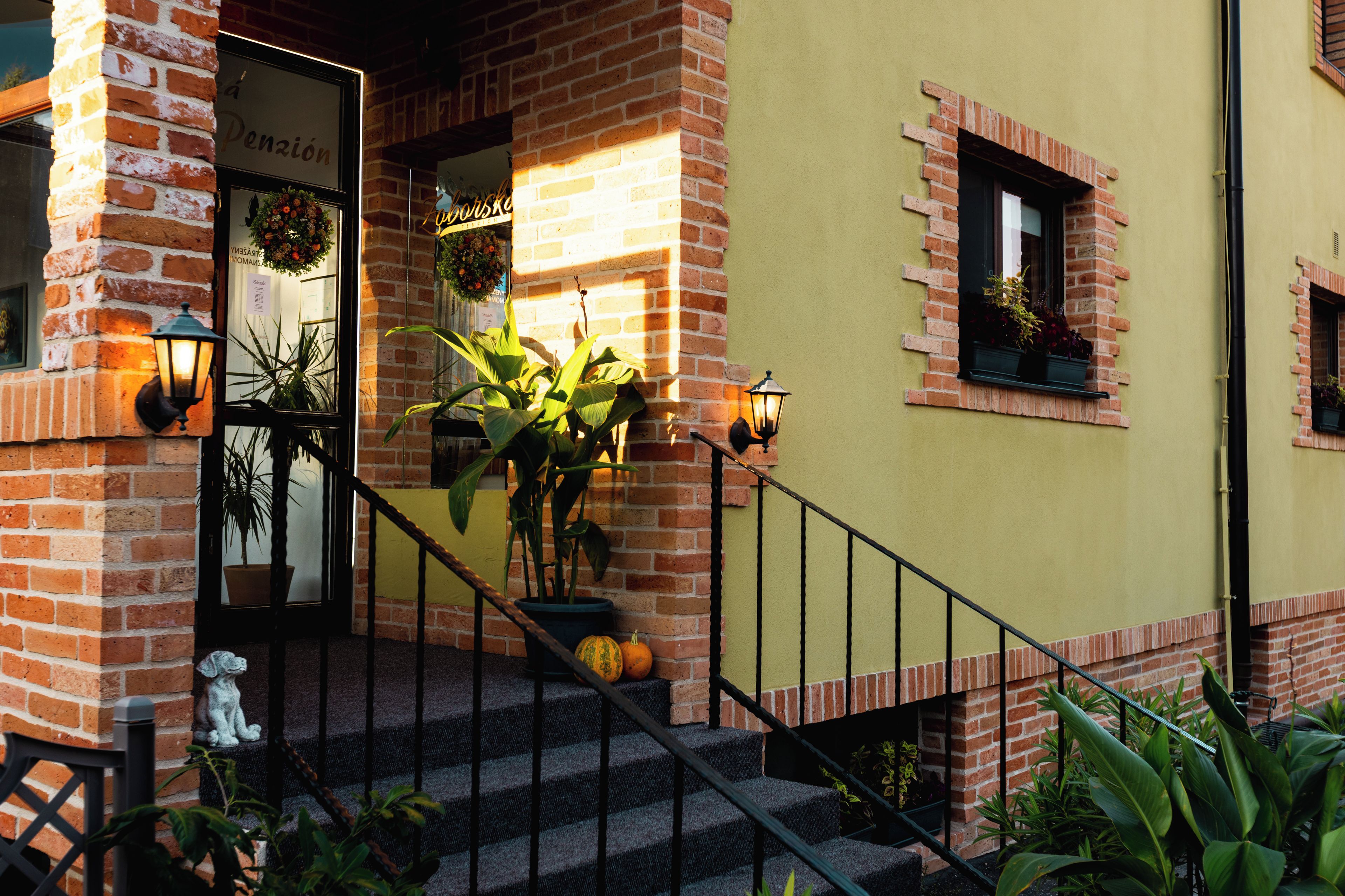 A brick building with a staircase leading to a door labeled 'Pension.'