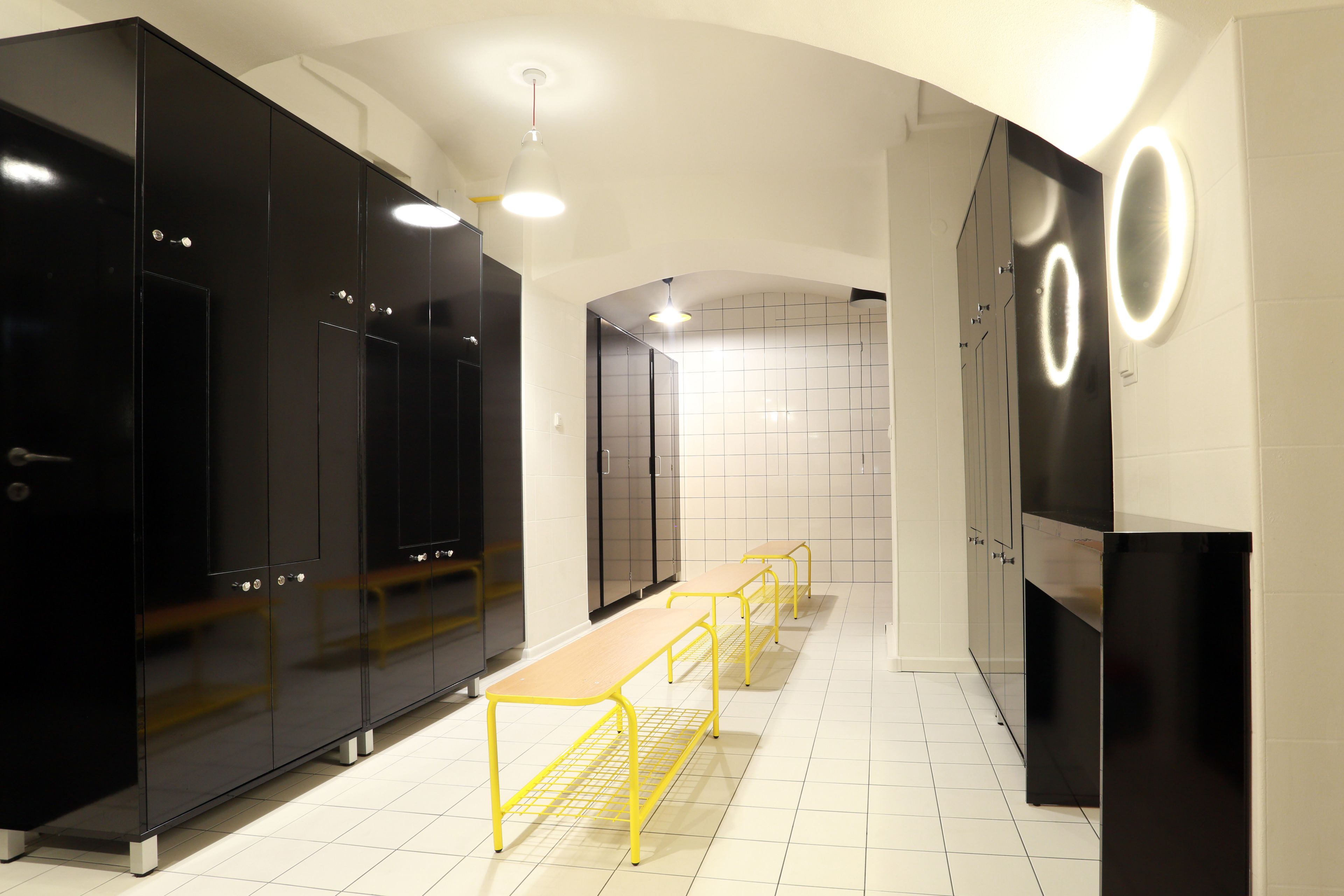 A modern bathroom with black cabinets, a bench, and a mirror with circular lights.