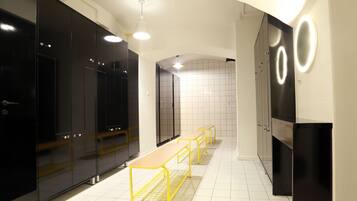 A modern bathroom with black cabinets, a bench, and a mirror with circular lights.