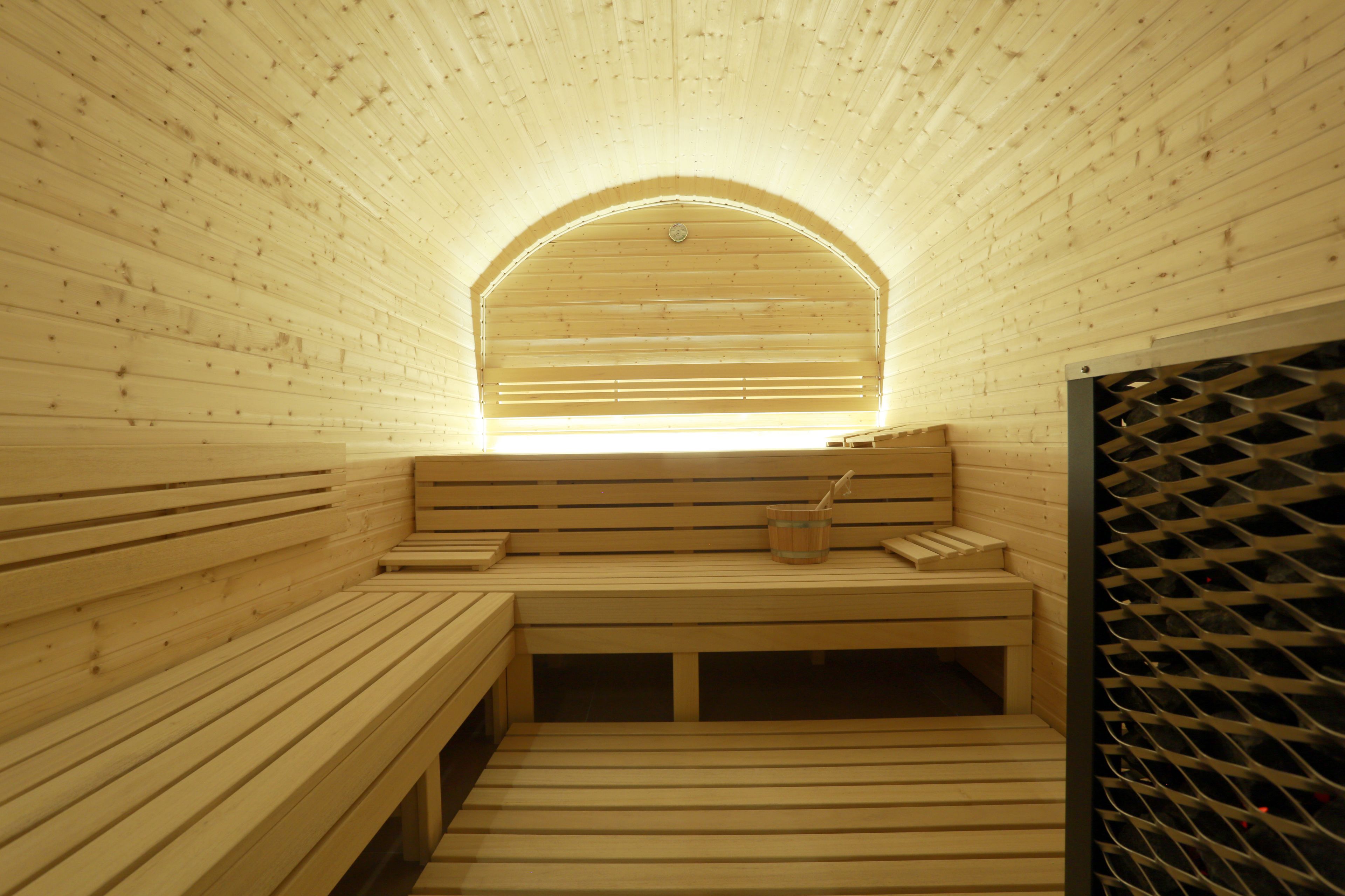 Una sauna con bancos de madera y uno con un vaso de agua.