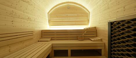 Una sauna con bancos de madera y uno con un vaso de agua.