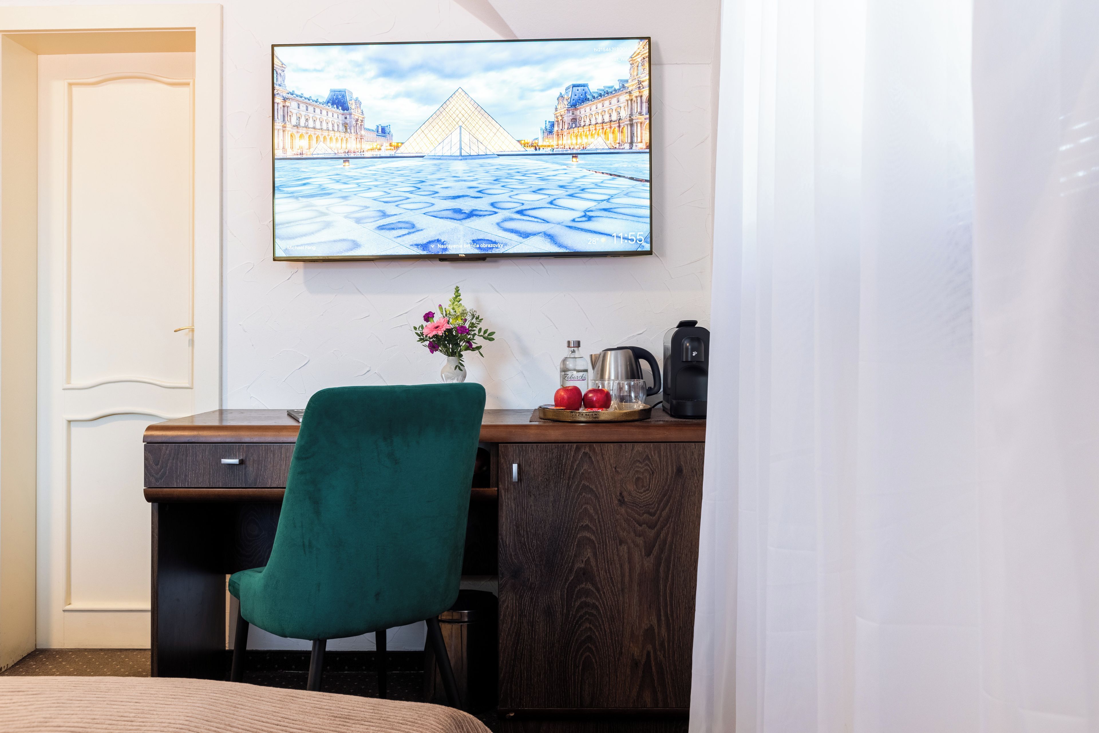 Una habitación de hotel con una cama, un escritorio con un florero, una tetera y una cafetera.