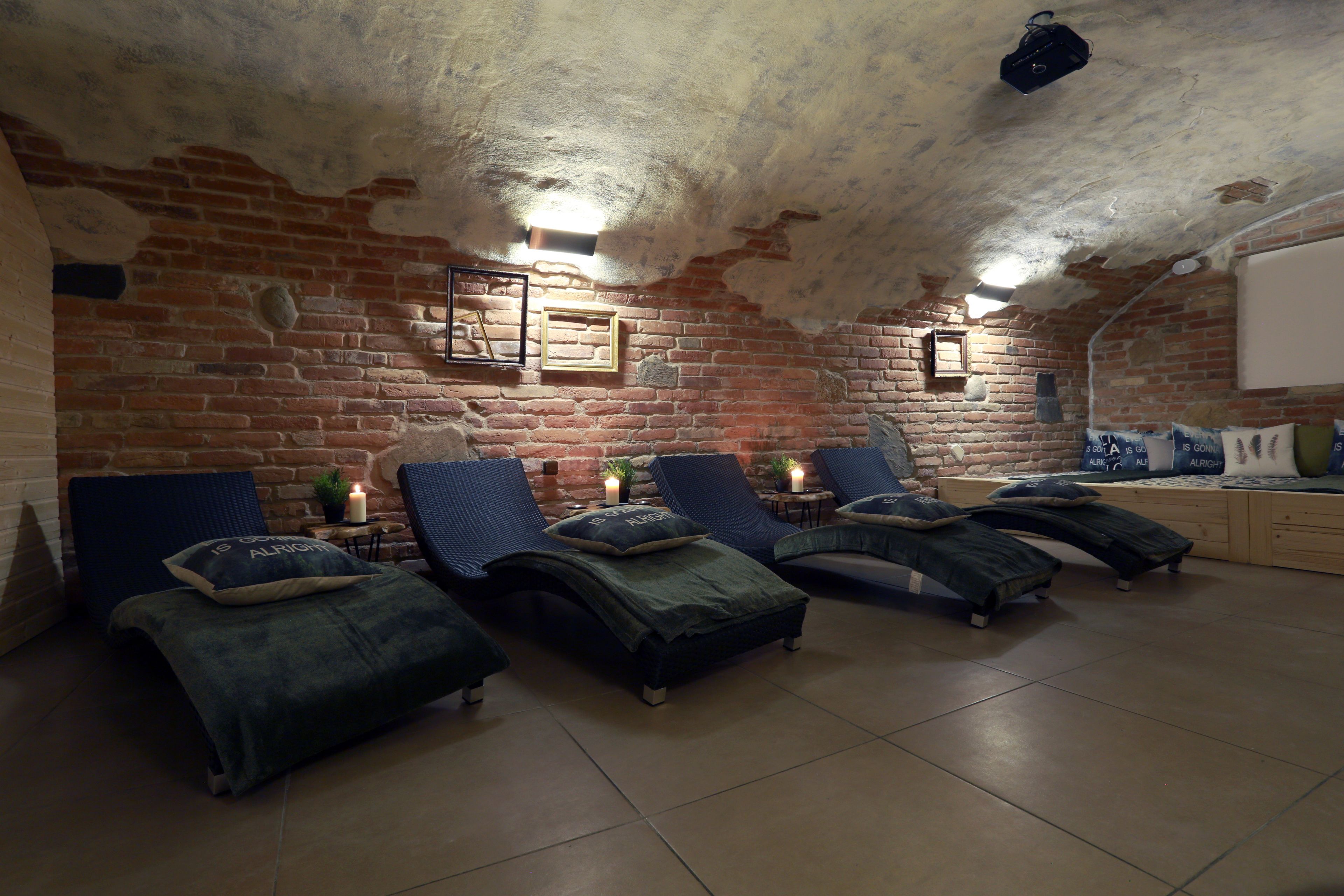 Une pièce chaleureuse avec quatre fauteuils confortables, un mur en briques et un projecteur fixé au plafond.