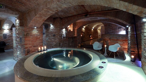 A spa area with a hot tub, brick walls, and seating. - Penzión & Wellness Zoborská (Nitra)