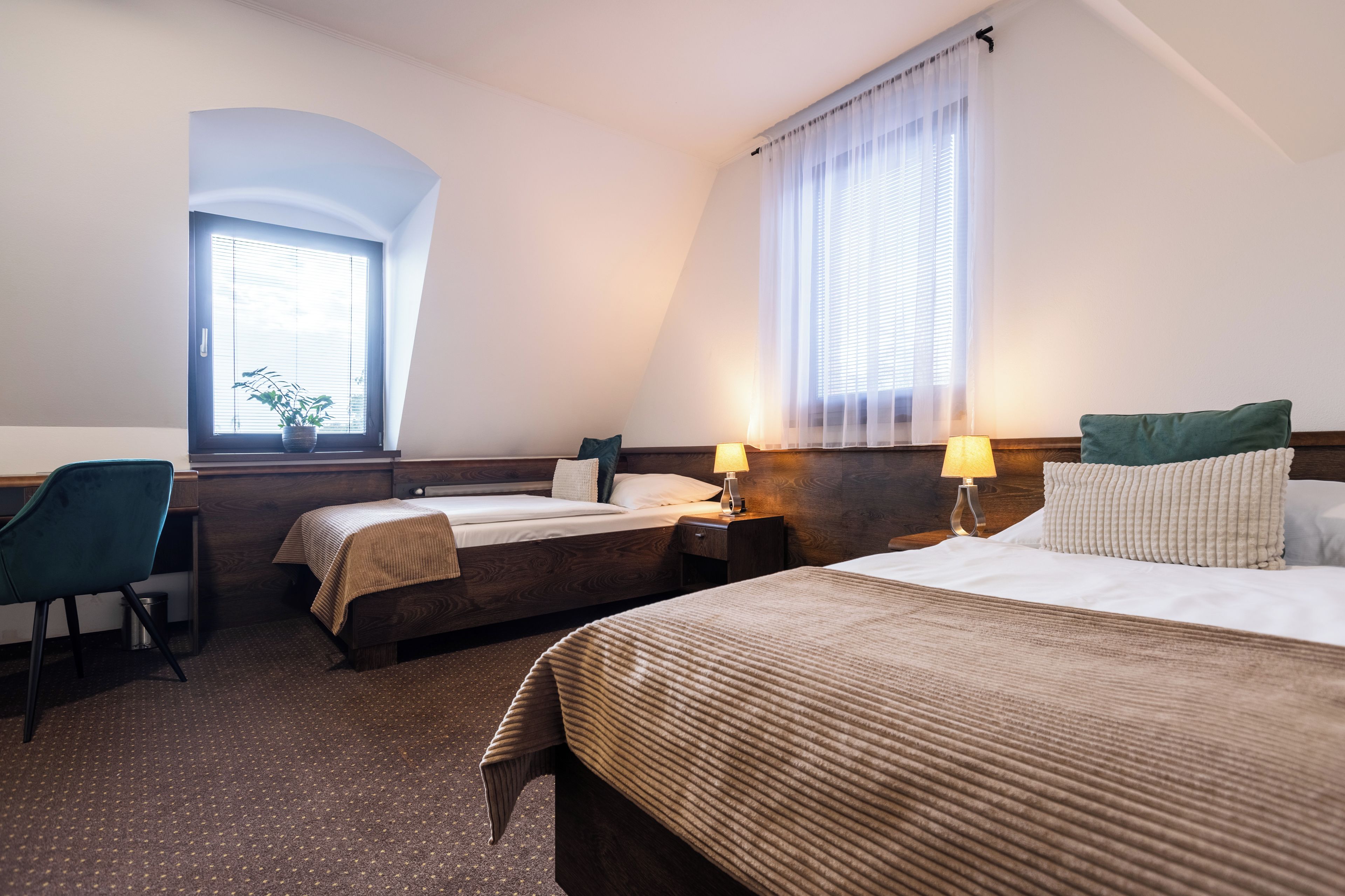 Een hotelkamer met twee bedden, een bureau en een stoel.
