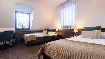 Een hotelkamer met twee bedden, een bureau en een stoel.
