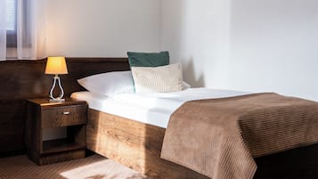 Une chambre d’hôtel avec un lit, une table de chevet, une lampe, une fenêtre avec des rideaux et un tableau accroché au mur.