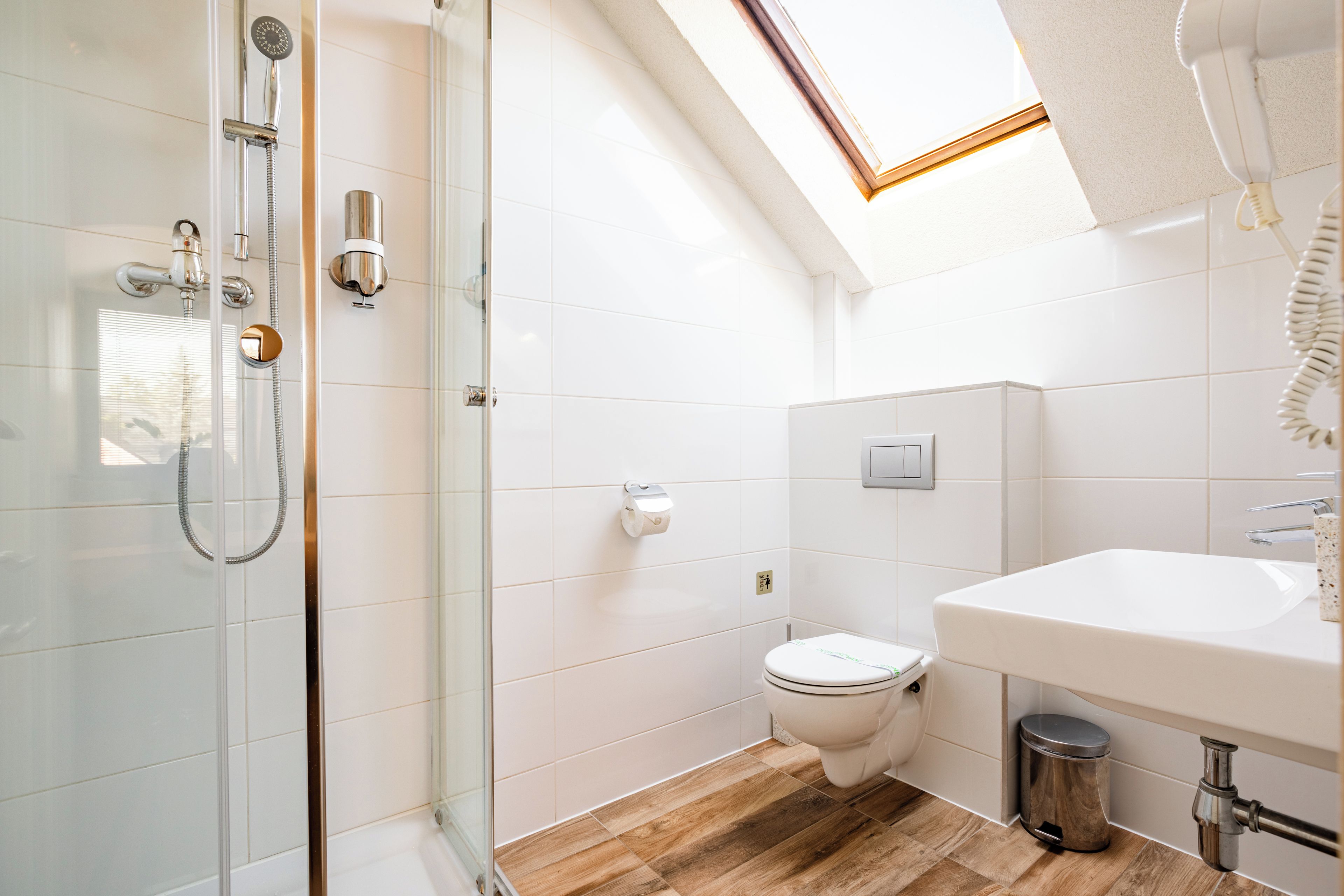A modern bathroom with a glass-enclosed shower, a toilet, and a sink.