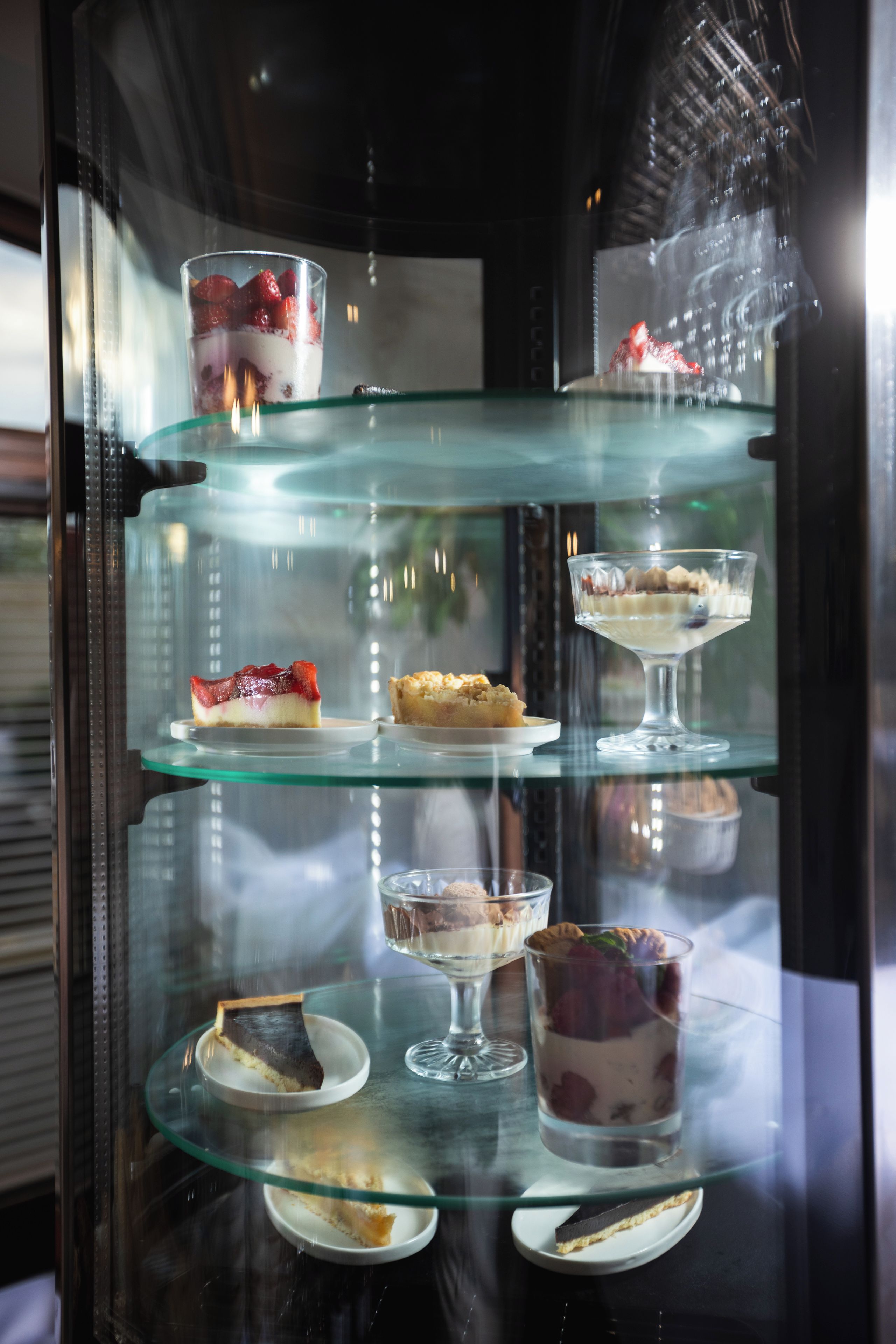 A dessert display case with various desserts on multiple shelves.