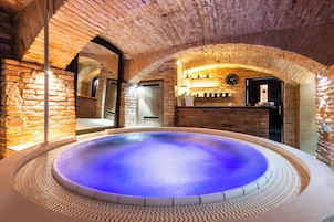 Un espacio de spa con un jacuzzi, paredes de ladrillo y una zona de bar con estantes y un reloj.