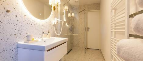 A modern bathroom with a white vanity, a large mirror, and a shower area.