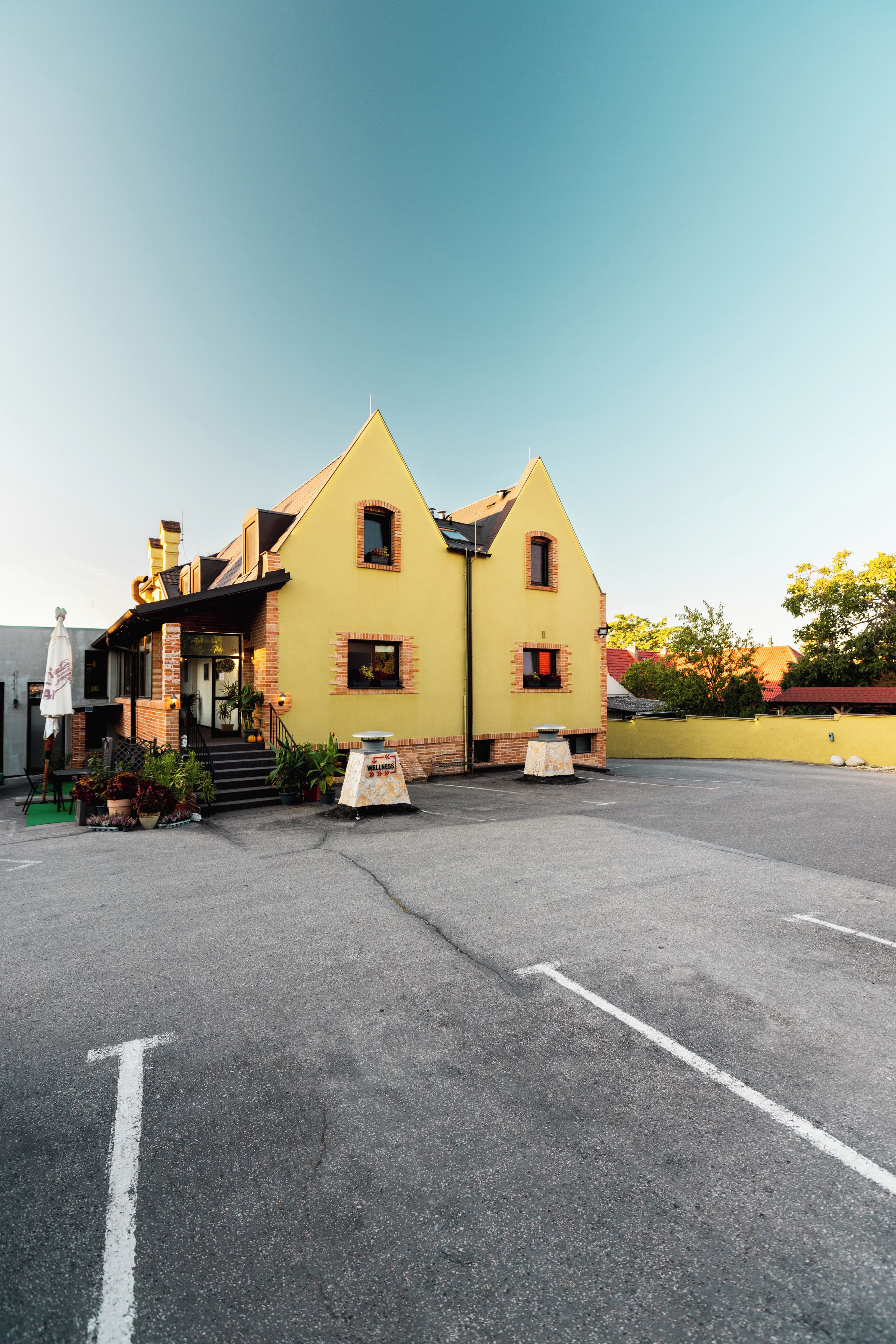 Un edificio amarillo con fachada de ladrillo, un porche y un letrero que dice 'Wellness'.