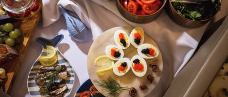 Une table sur laquelle on trouve divers aliments, notamment des légumes coupés en tranches, un saladier de tomates et une assiette d’œufs mimosa garnis de caviar.