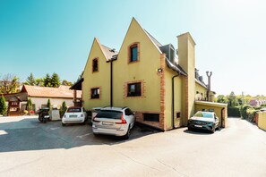 A yellow building with a sloped roof, a car parked in front, and a small wooden structure to the left. - Penzión & Wellness Zoborská (Nitra)