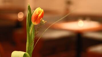 Een detail van een enkele oranje tulp in een vaas, met een onscherpe achtergrond.