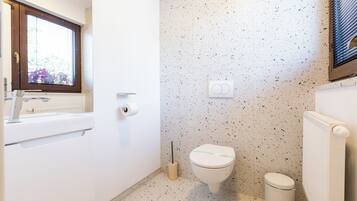 Un baño con inodoro, bidé, lavamanos y ventana.