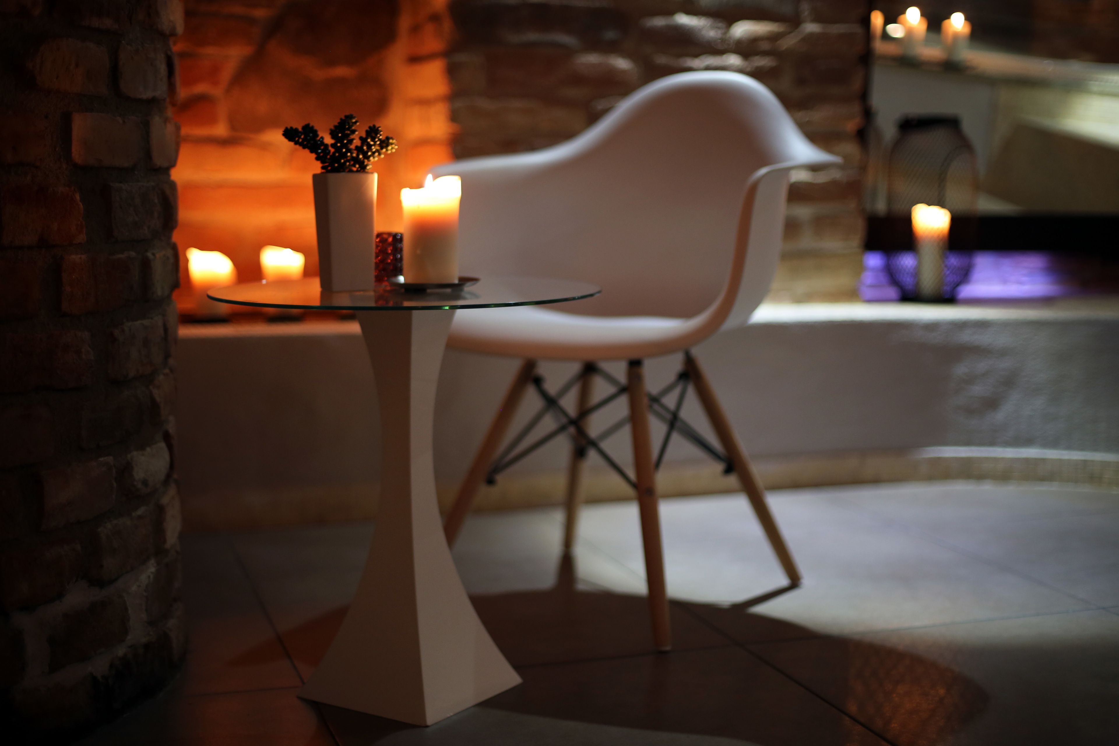 Un interior moderno con una mesa de vidrio, una silla blanca y velas.