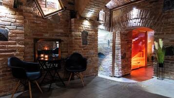Un interior rústico con paredes de ladrillo visto, chimenea y asientos modernos.