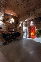 Un interior rústico con paredes de ladrillo visto, chimenea y asientos modernos.