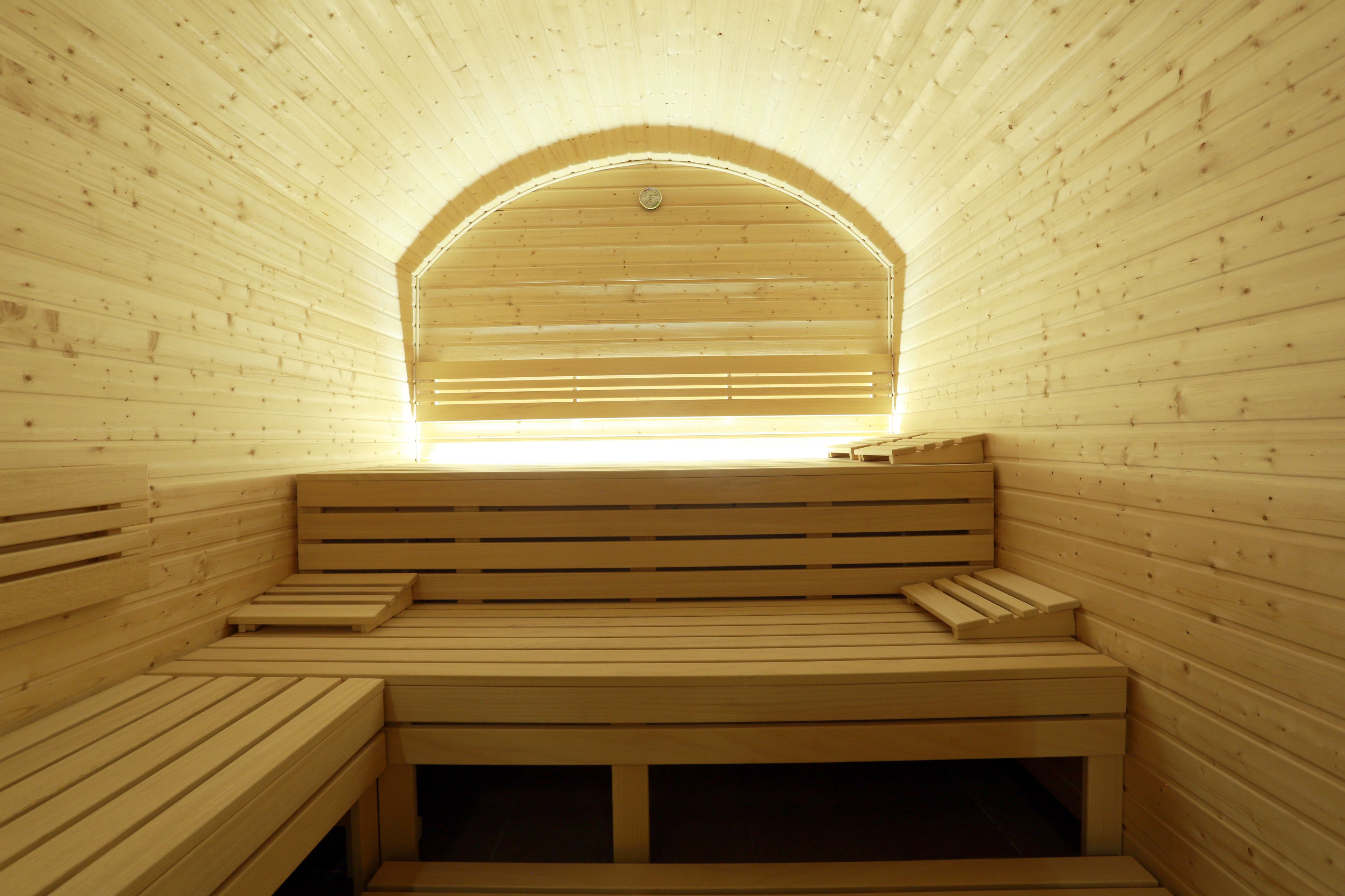 A sauna with wooden benches and a sloped ceiling.