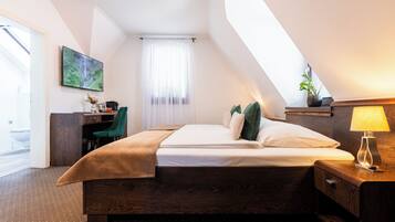 A hotel room with a bed, a desk, a chair, a lamp, and a window with curtains.