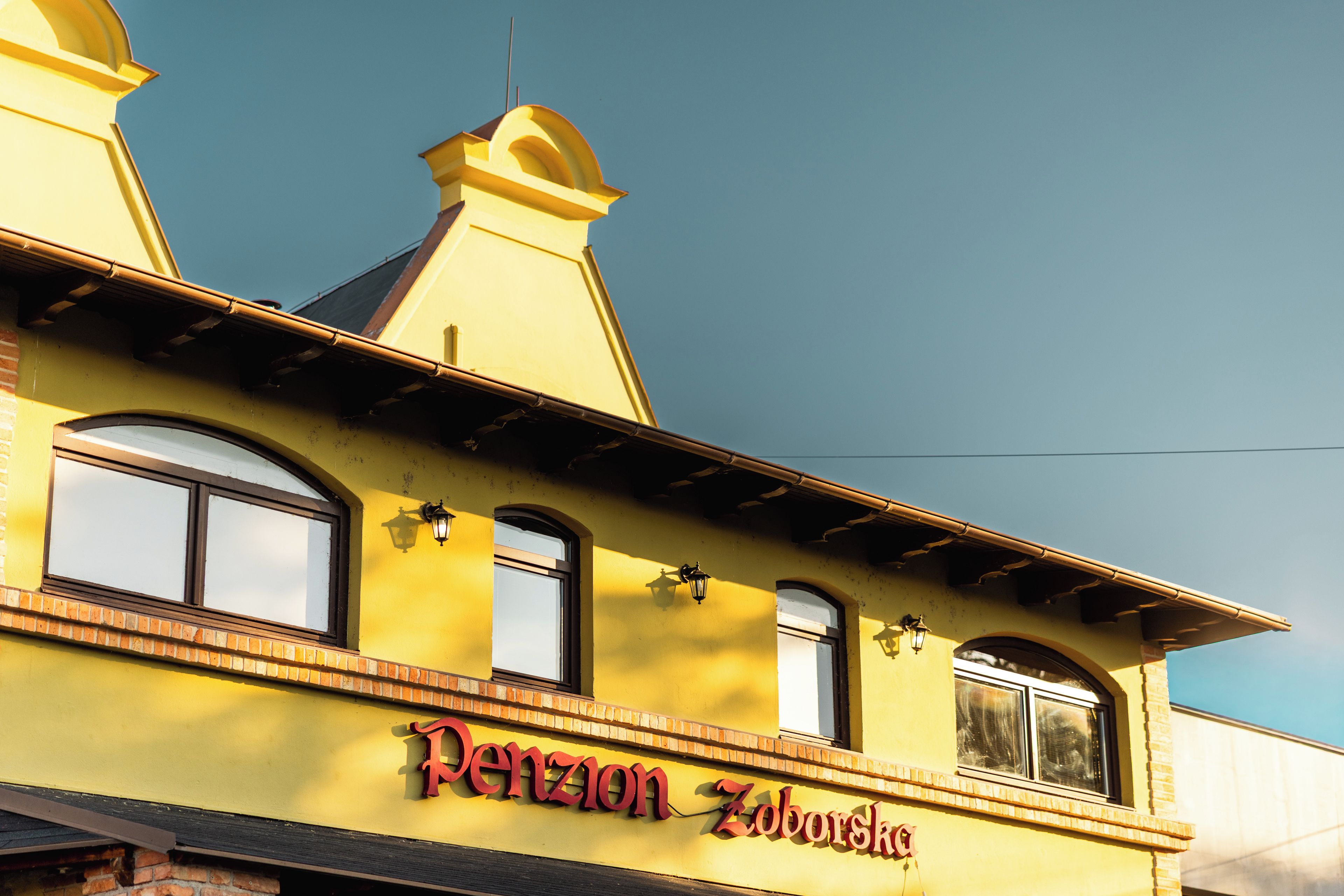 A yellow building with the name 'Denzon Zoborsk' on the facade.