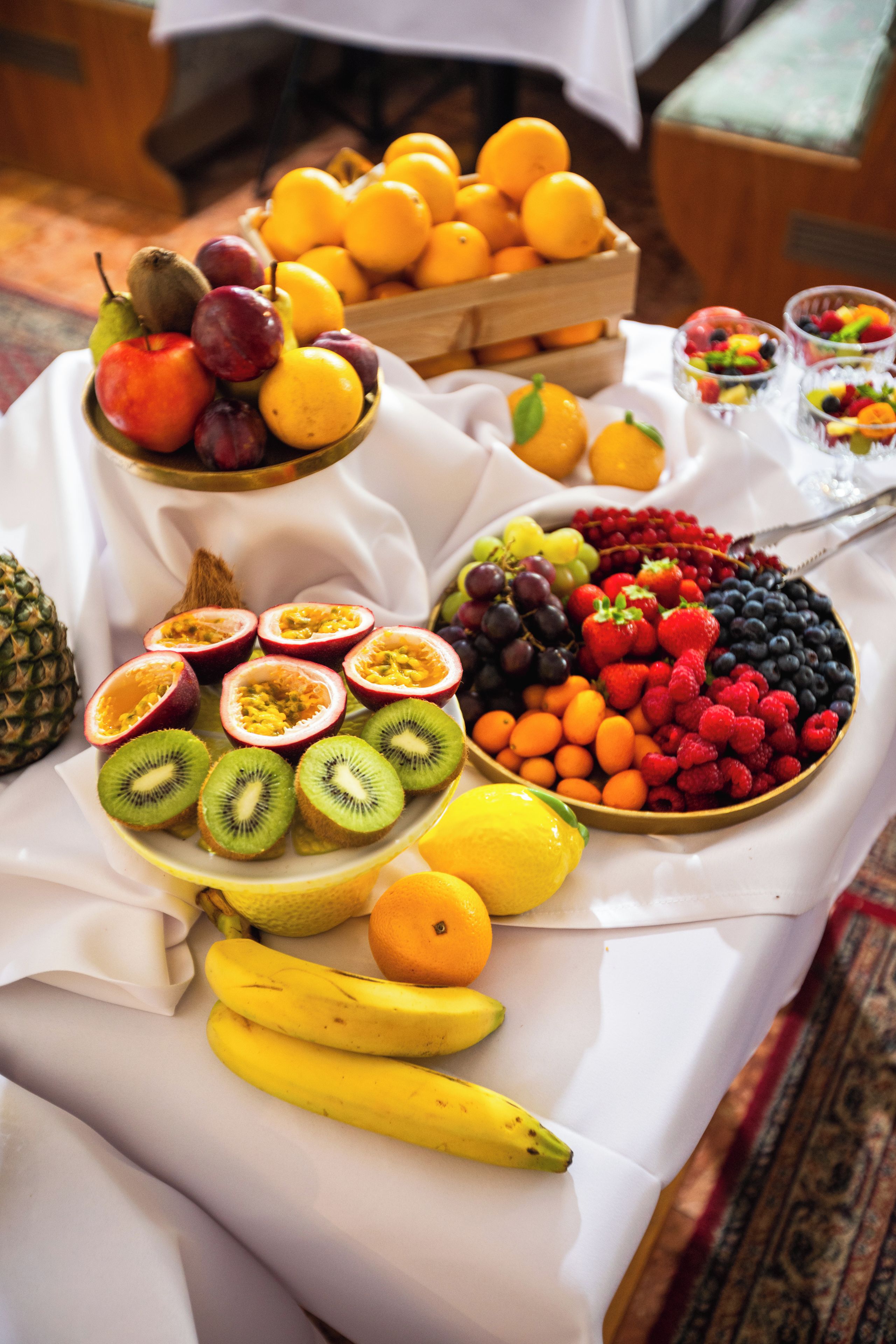 Une table avec différents fruits et un bol de fruits rouges mélangés.