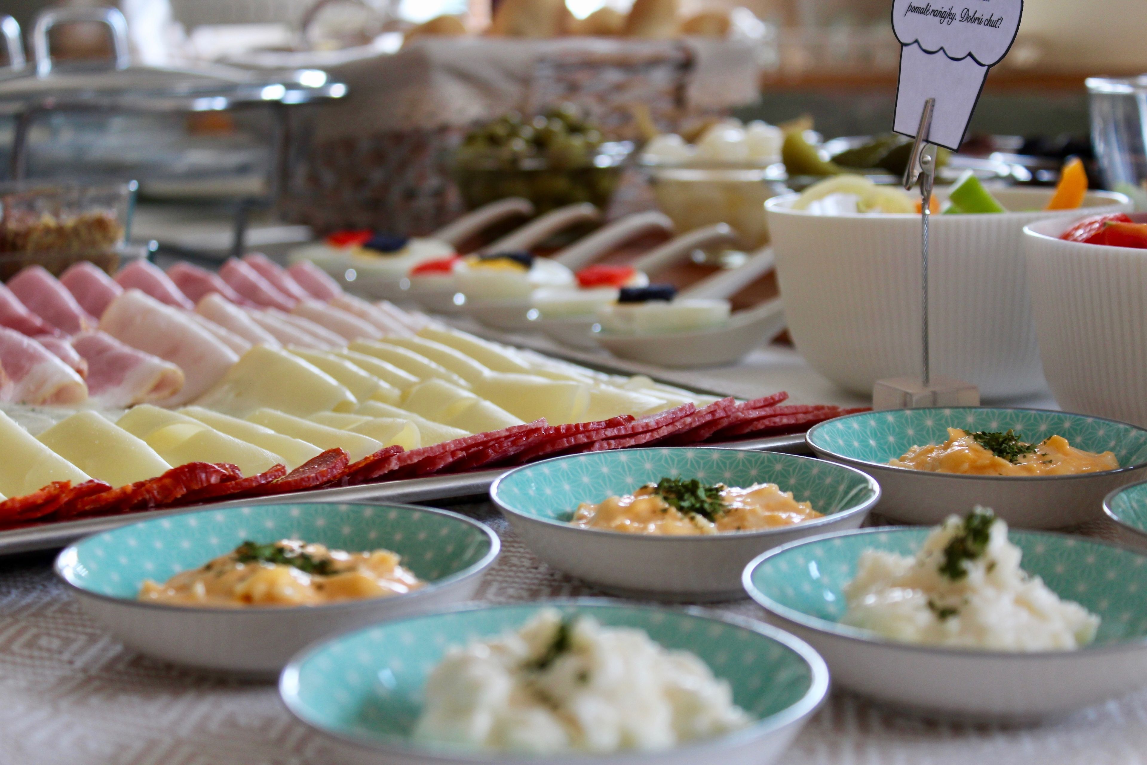 A buffet with various dishes including meats, cheeses, and salads.