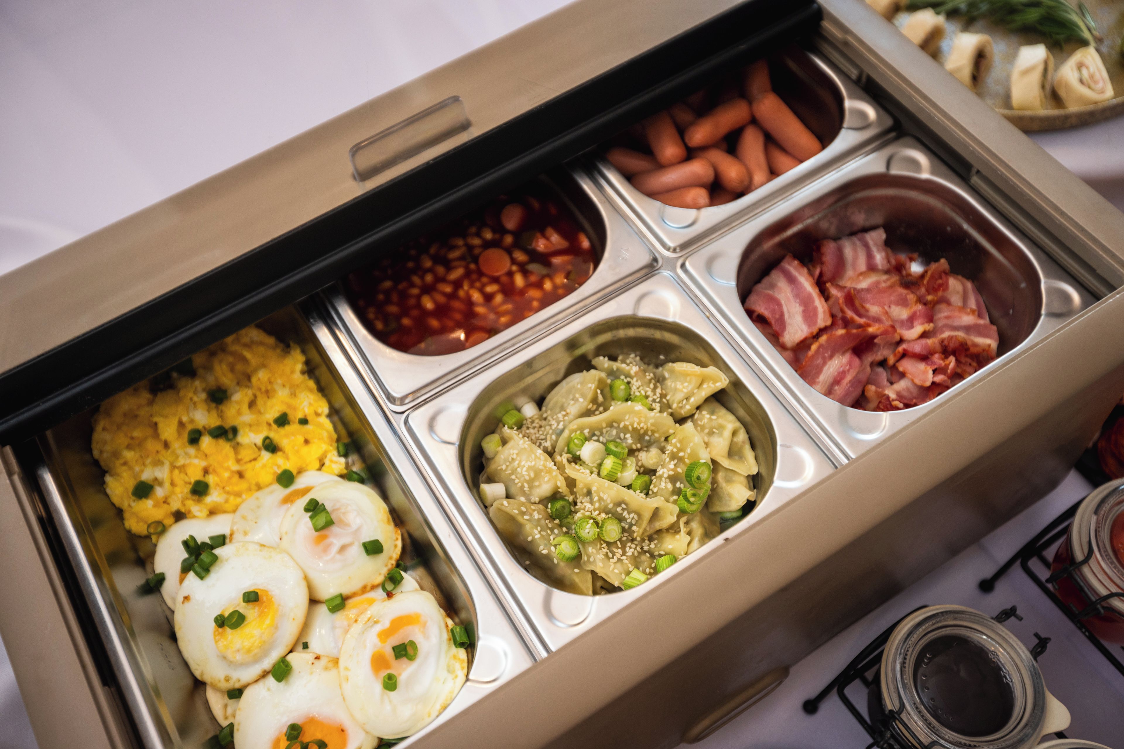 A meal tray with various food items including eggs, beans, and meat.