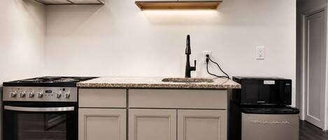 A kitchen with a stove, oven, microwave, and a sink.