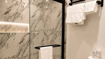 A modern bathroom with a glass-enclosed shower, a toilet, and a towel rack.
