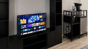 A modern living room with a flat-screen TV, black entertainment unit, and a coffee machine. - Lake George Residence LLC (South Glens Falls)