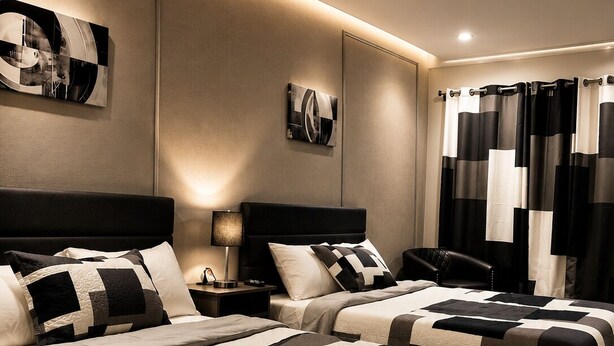 A hotel room with two beds, a nightstand, a lamp, and a wall-mounted artwork. - Lake George Residence LLC (South Glens Falls)