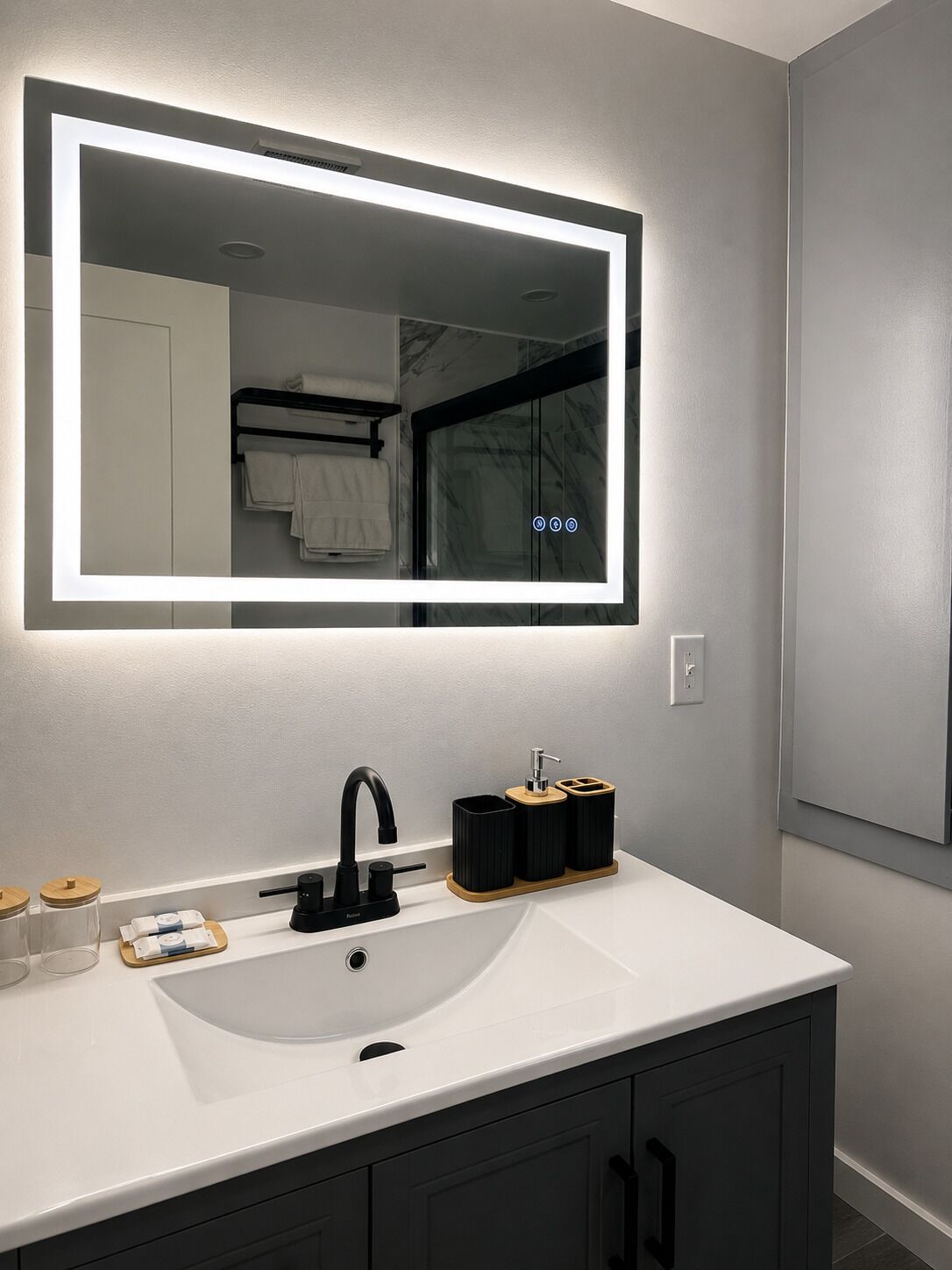 A bathroom with a white sink, black faucet, and a mirror with LED lighting.