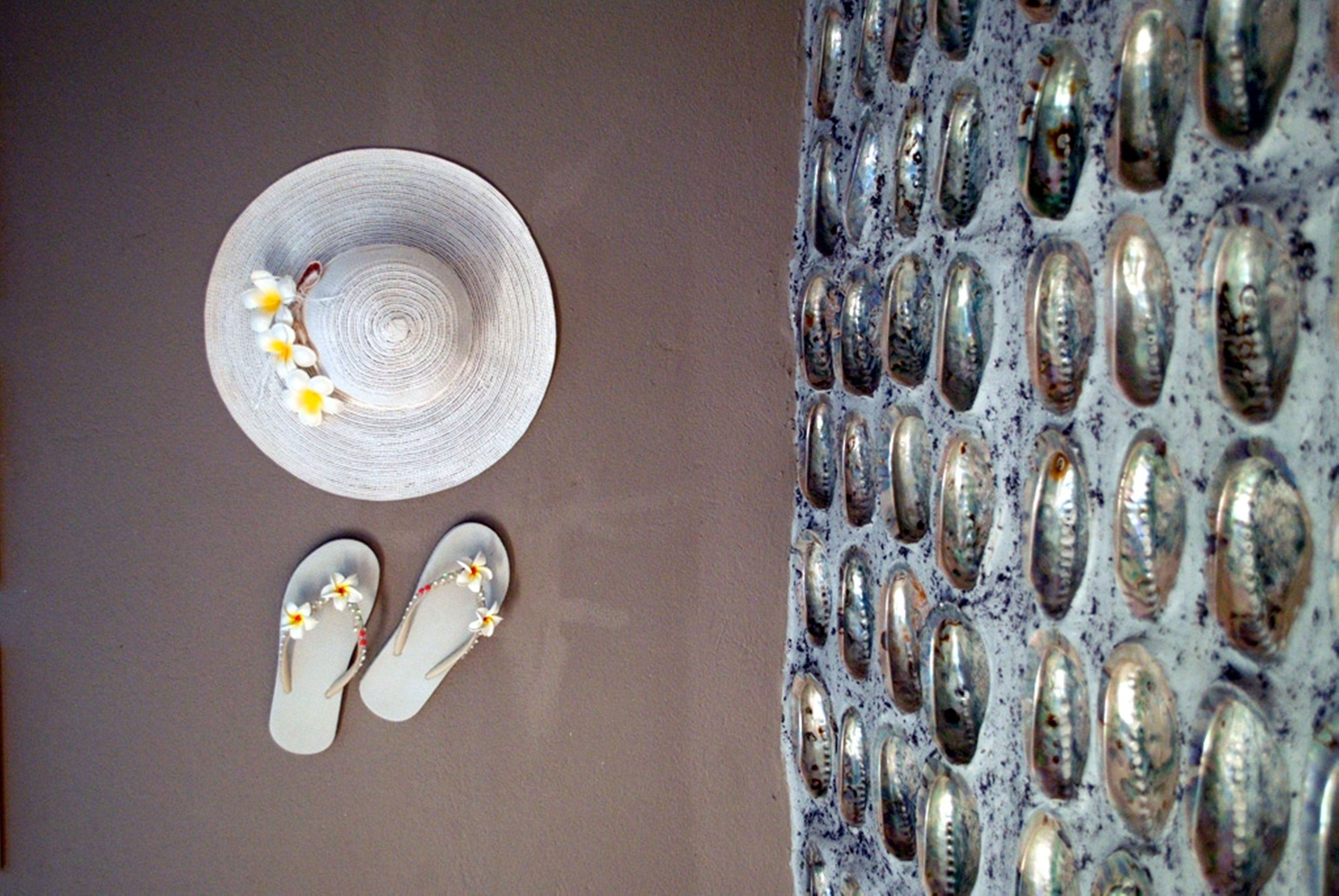 Een hoed, een paar slippers en een muur met reflecterende metalen details.
