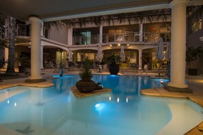 Un área de piscina con varios niveles, palmeras y sillas de descanso.