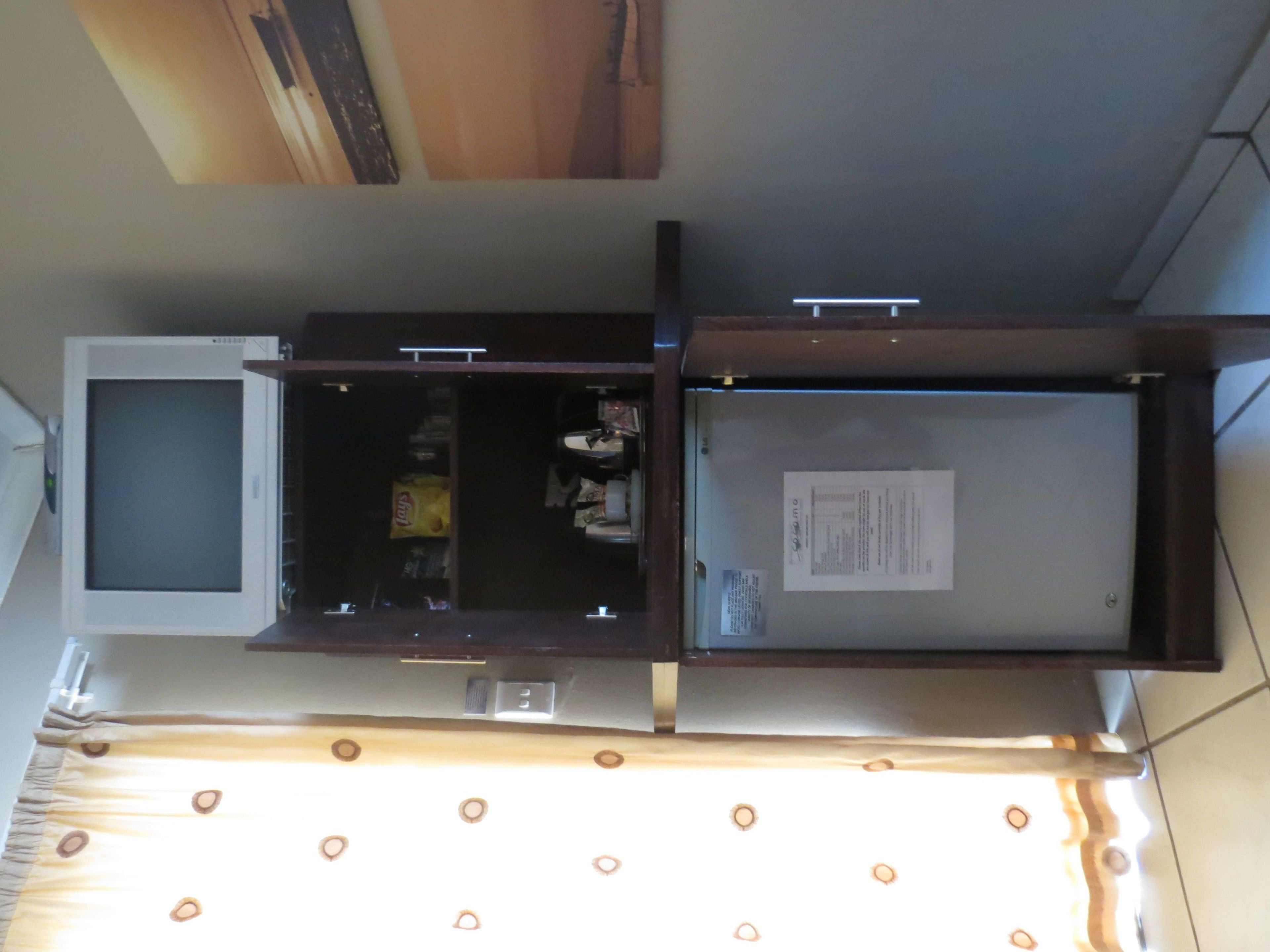 Una habitación con una televisión de pantalla plana grande, un mueble de madera y una mesita pequeña.