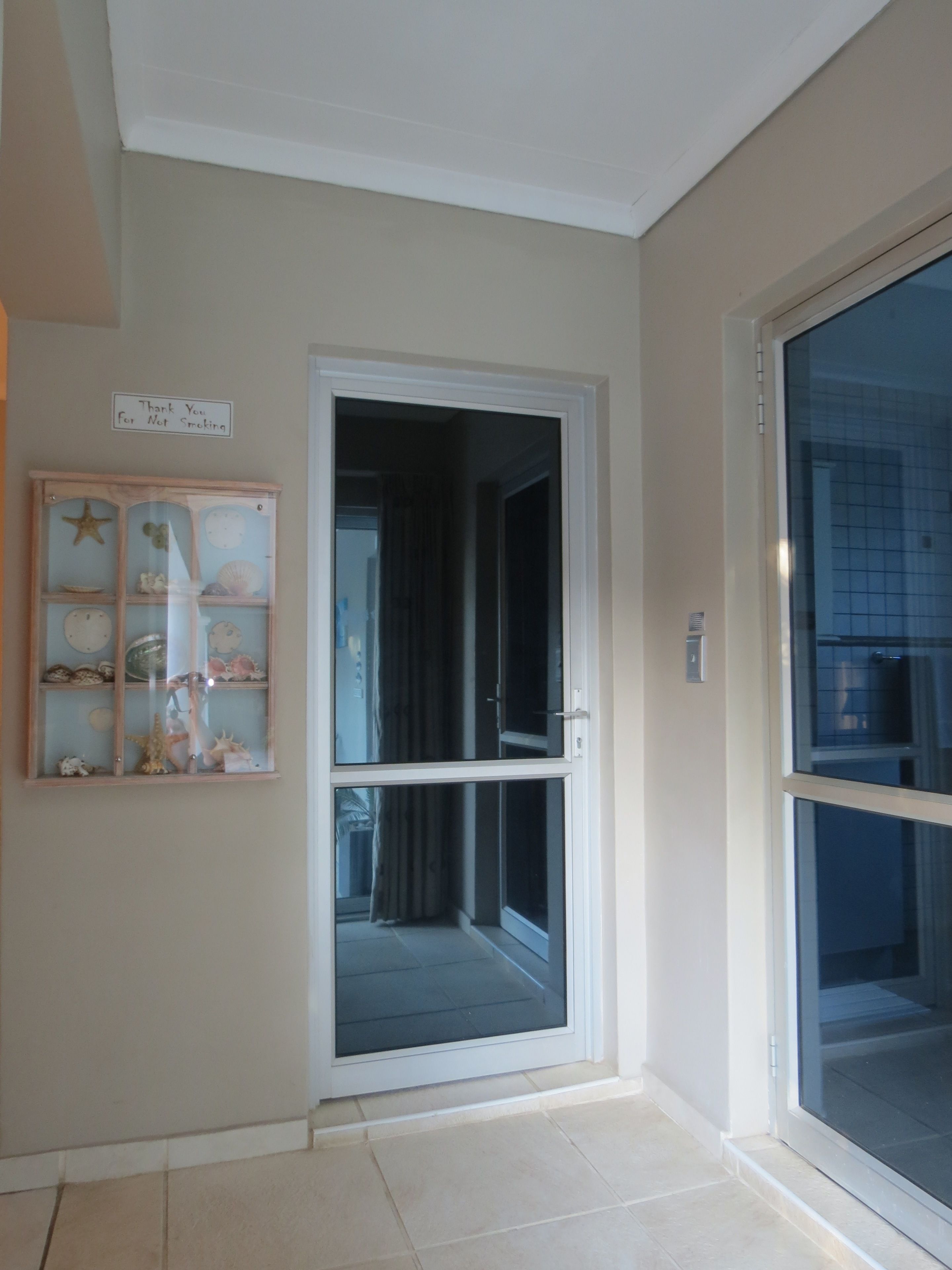 Ein Zimmer mit einer Schiebeglastür, die auf einen Balkon führt, einer kleinen Hollauslage mit Dekorationsobjekten und einem Schild an der Wand.