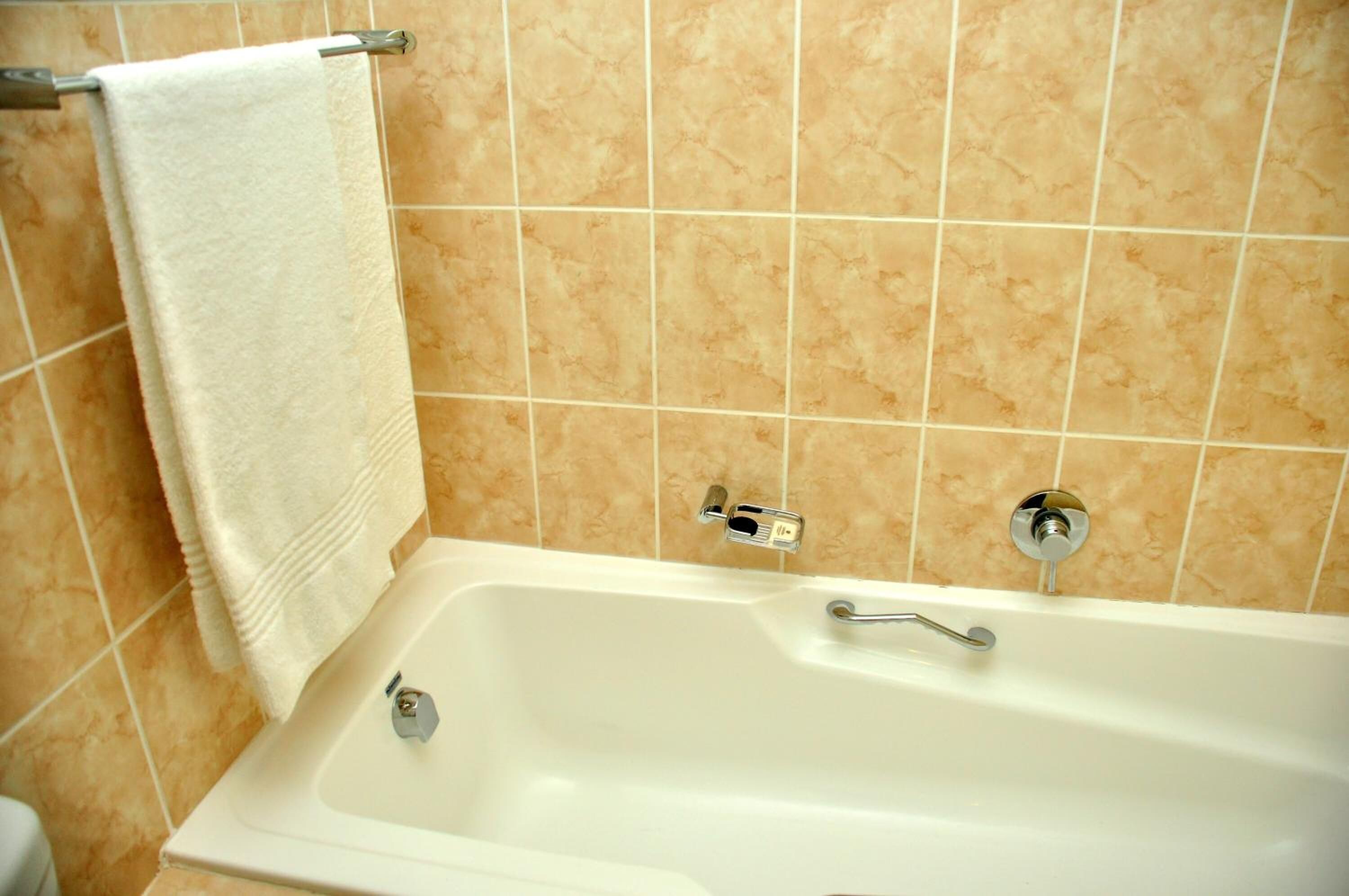A bathroom with a bathtub, a towel rack, and a toilet.